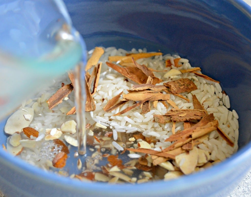 Horchata process adding water to soak rice, almonds, and cinnamon sticks. 