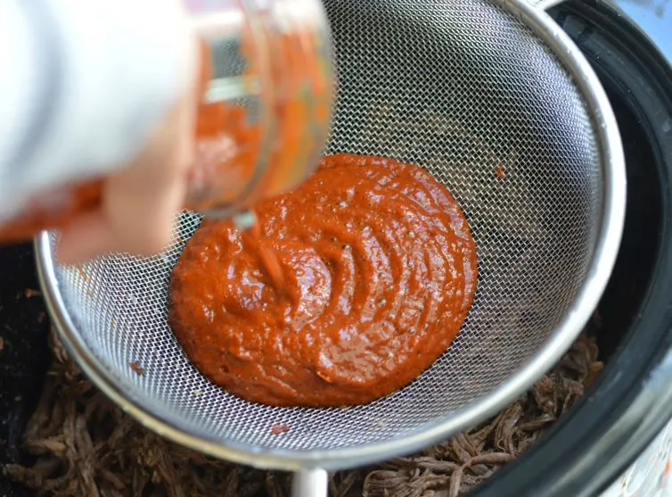 barbacoa sauce going through a strainer