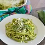Espagueti verde en un plato con queso y cilantro