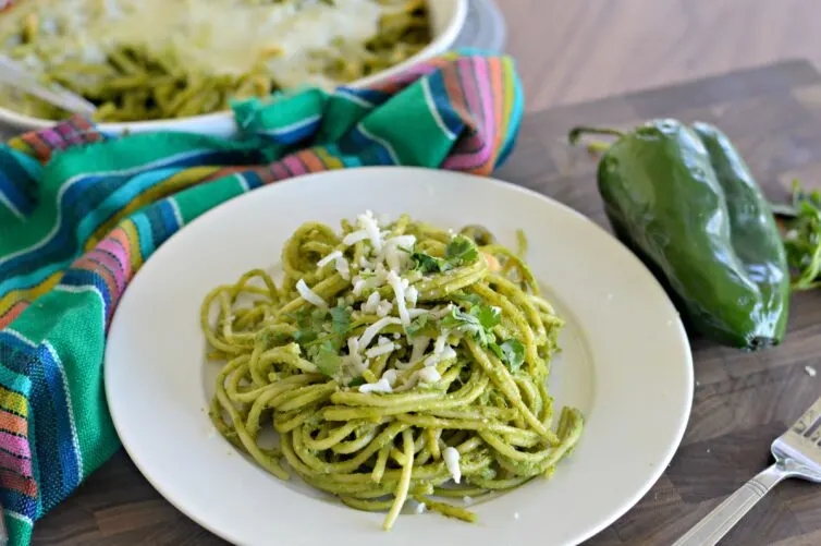Espagueti verde en un plato con queso y cilantro