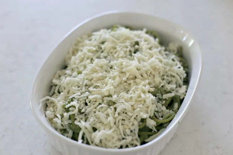 green spaghetti with mozzarrella cheese before being baked