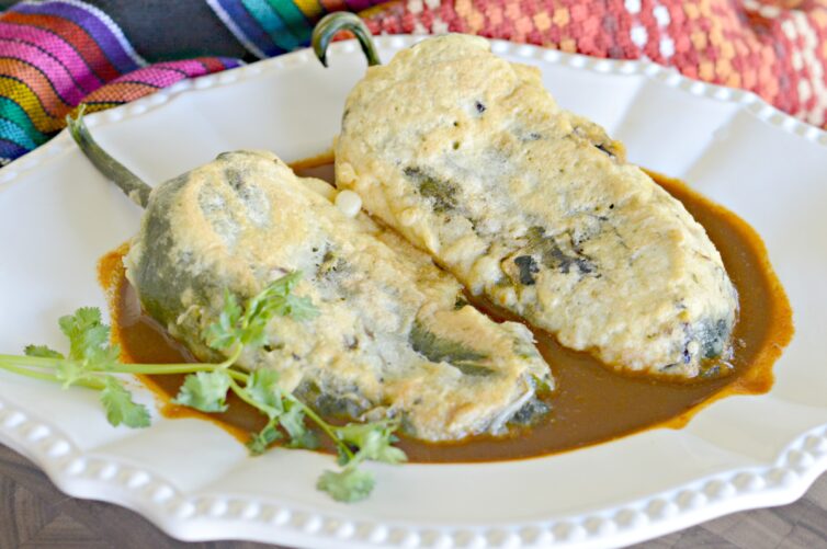 Picture showing chiles rellenos de queso in a bed of ancho chile salsa garnished with cilantro