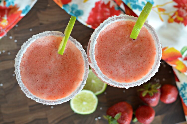 Two strawberry margarita mocktails in glasses with limes facing in the same direction