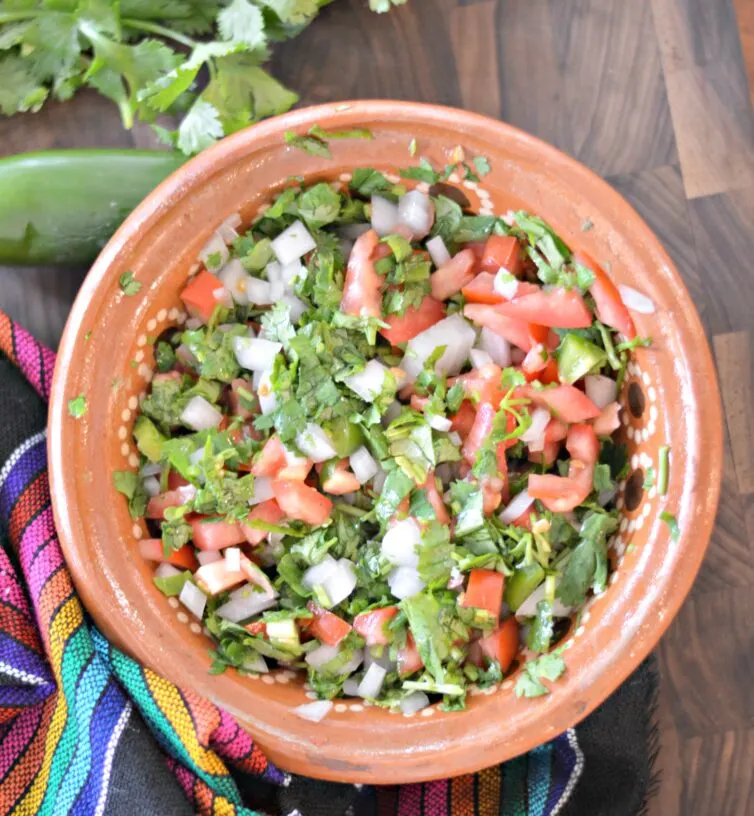 Pico de gallo in a bowl with a jalapeno next to it