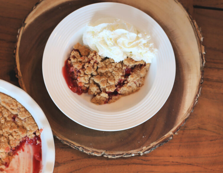 Smoked Cherry Cobbler with whipped cream on a wooden platter