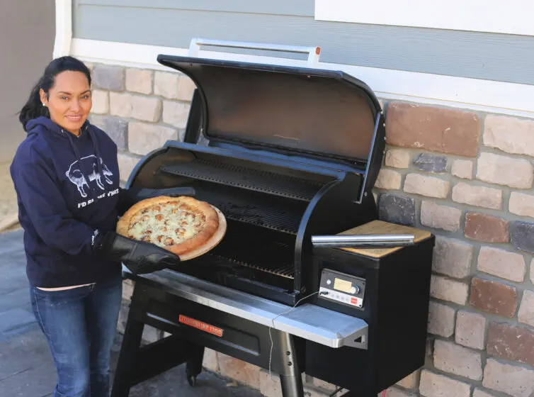 me holding a smoked pizza by a traeger timeberline 1300