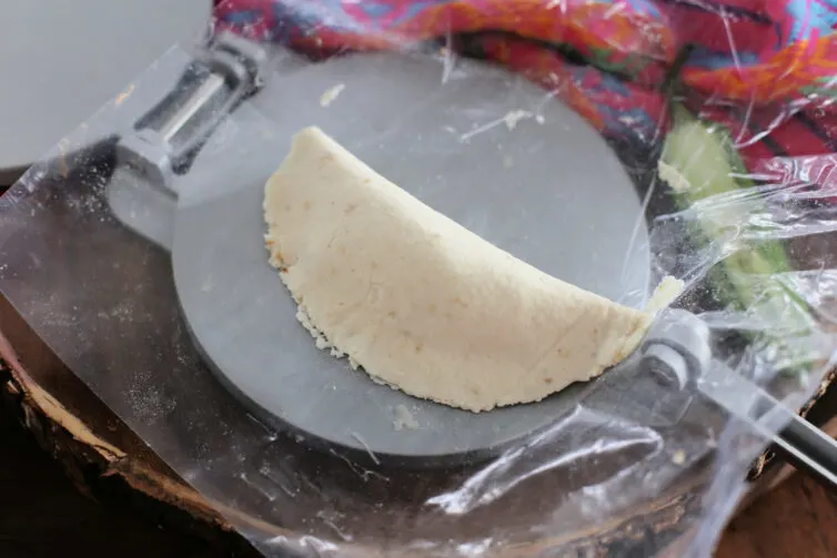 empanada on a tortilla press before frying it