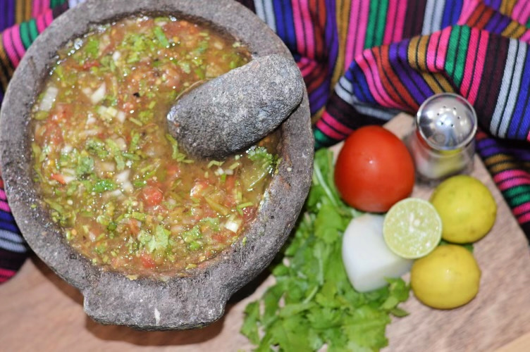 molcajete salsa in a molcajete stone with ingredients next to it
