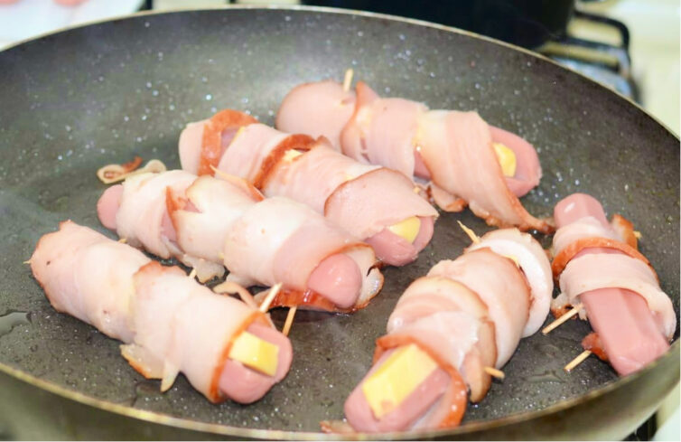 sausages wrapped in bacon and filled with cheese being grilled