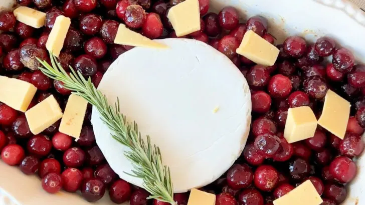 cranberries in a baking dish with gouda, brie, and rosemary