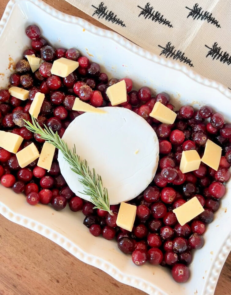 cranberries in a baking dish with gouda, brie, and rosemary