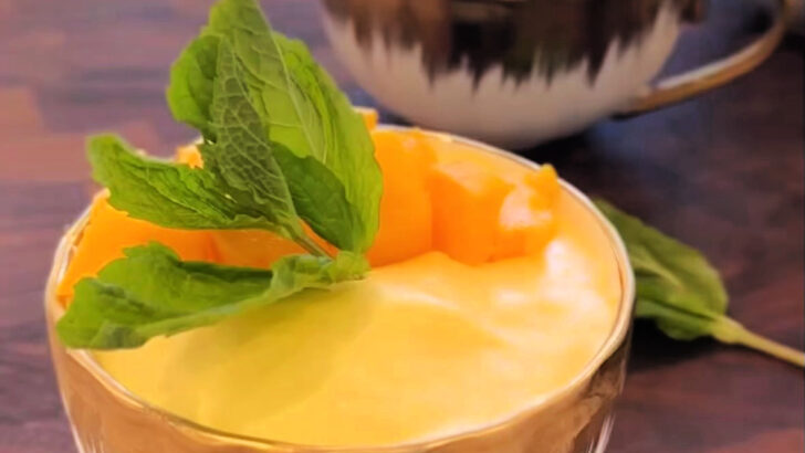 mango mousse in a cute gold and white bowl with a mint leaf on top