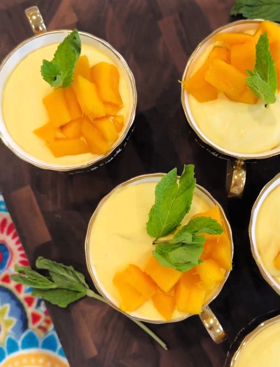 three mango mousse bowls on a wooden board