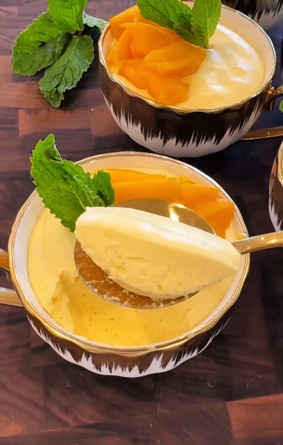 Mango mousse being scooped out with a golden colored spoon