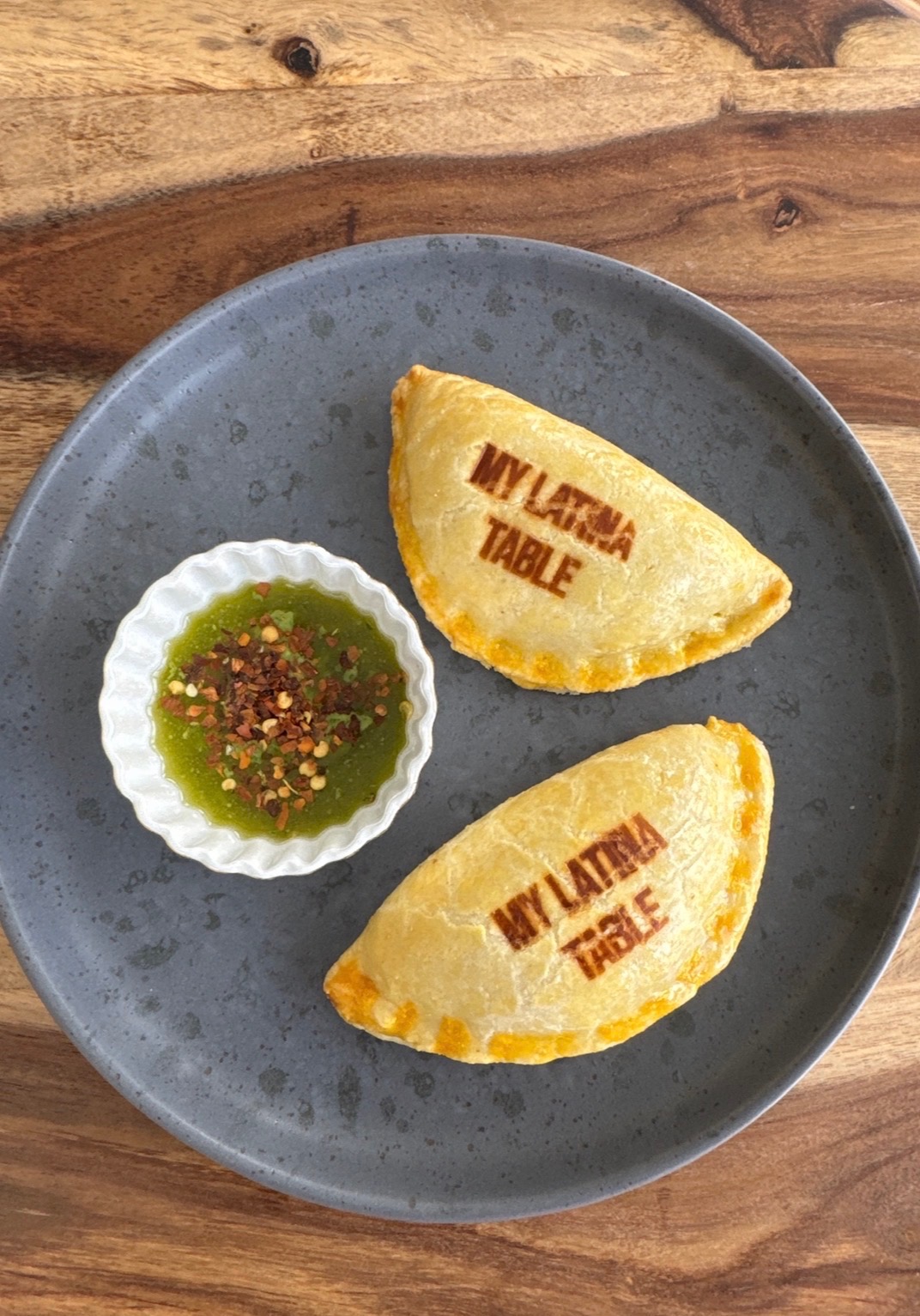 empanadas en un plato gris con chimichurri a lado